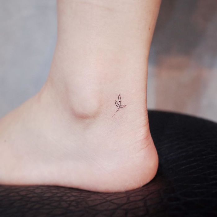 Minimalist tattoo of a tiny leaf on an ankle, showcasing discreet art for tattoo lovers.