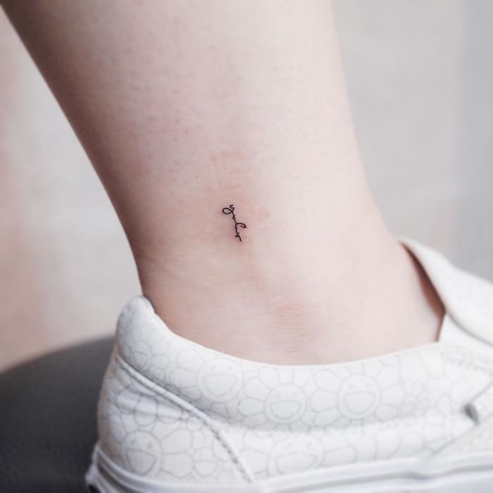 Minimalist tiny tattoo on ankle above white sneaker.