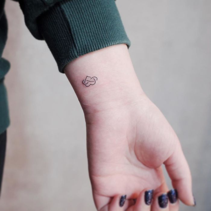 Minimalist wrist tattoo of a small heart on a person's arm, showcasing tiny discreet body art.