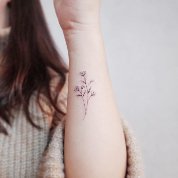 Minimalism tattoo of a small floral design on forearm, perfect for lovers of discreet ink art.