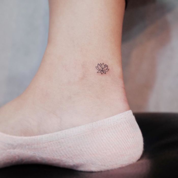 Minimalism tattoo featuring a tiny lotus design on an ankle wearing a light pink sock.