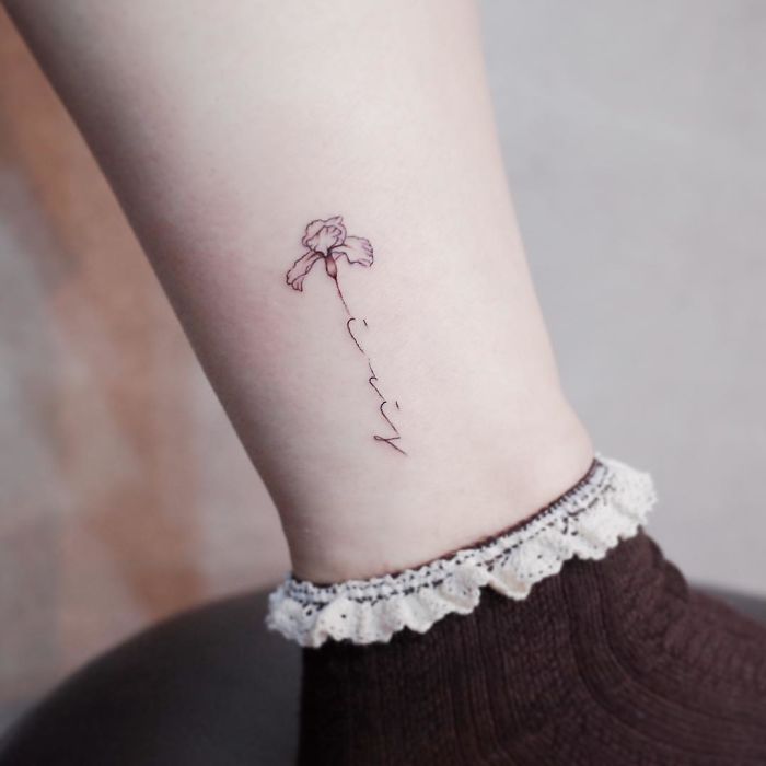 Minimalism tattoo featuring a tiny, discreet flower design on an ankle, above lacy sock trim.