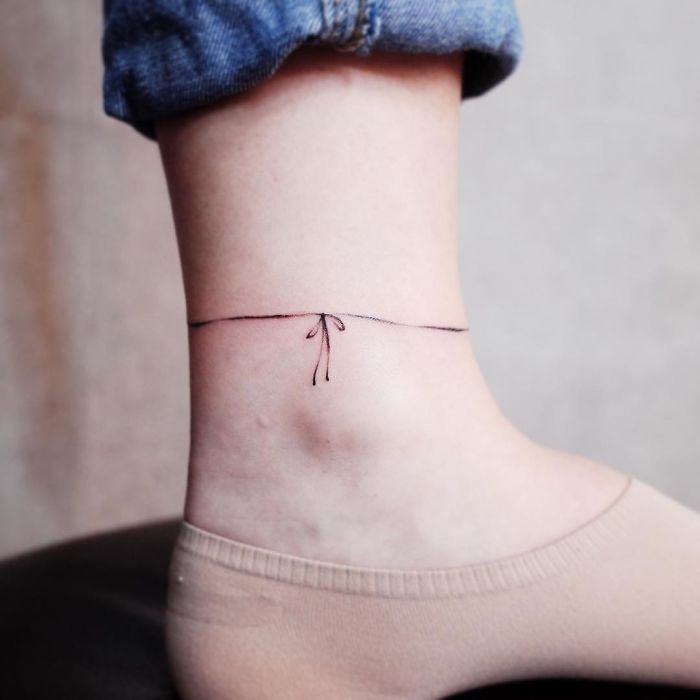 Minimalistic tattoo on ankle resembling a thin line with a bow, ideal for those who love discreet designs.
