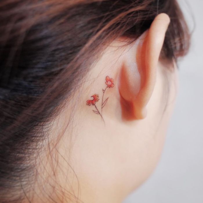Minimalist tiny flower tattoo behind an ear, showcasing discreet tattoo artistry.