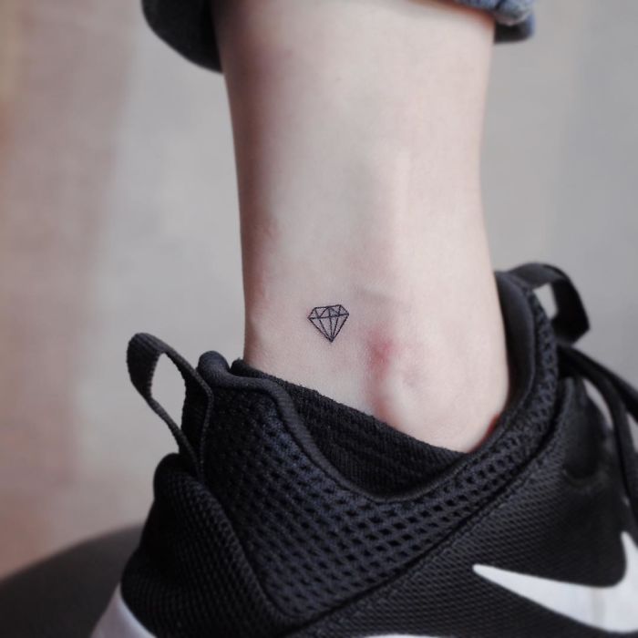 Minimalist diamond tattoo on ankle above black sneaker.