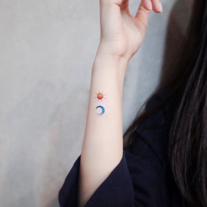 Minimalist tiny sun and moon tattoos on a person's forearm.