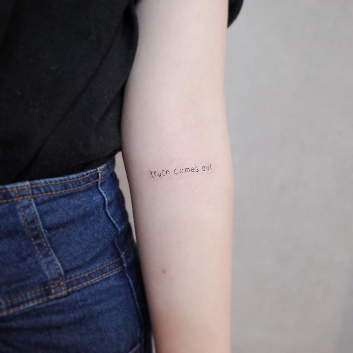 Minimalist tattoo on forearm reads "truth comes out," showcasing discreet body art style.