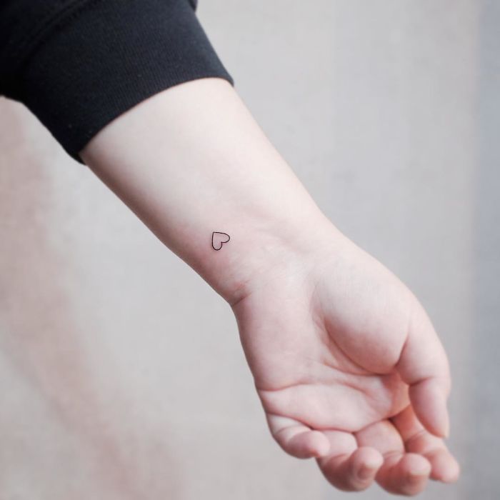 Minimalist tiny heart tattoo on wrist, perfect for those who love discreet designs.