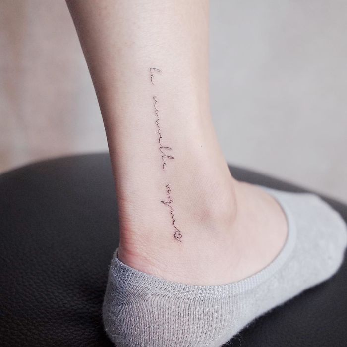 Minimalism tattoo with delicate script on an ankle, showcasing discreet design.