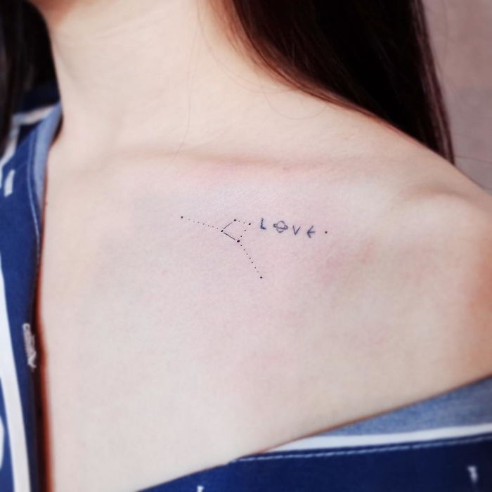 Minimalism tattoo featuring constellation and the word "love" on woman's collarbone.