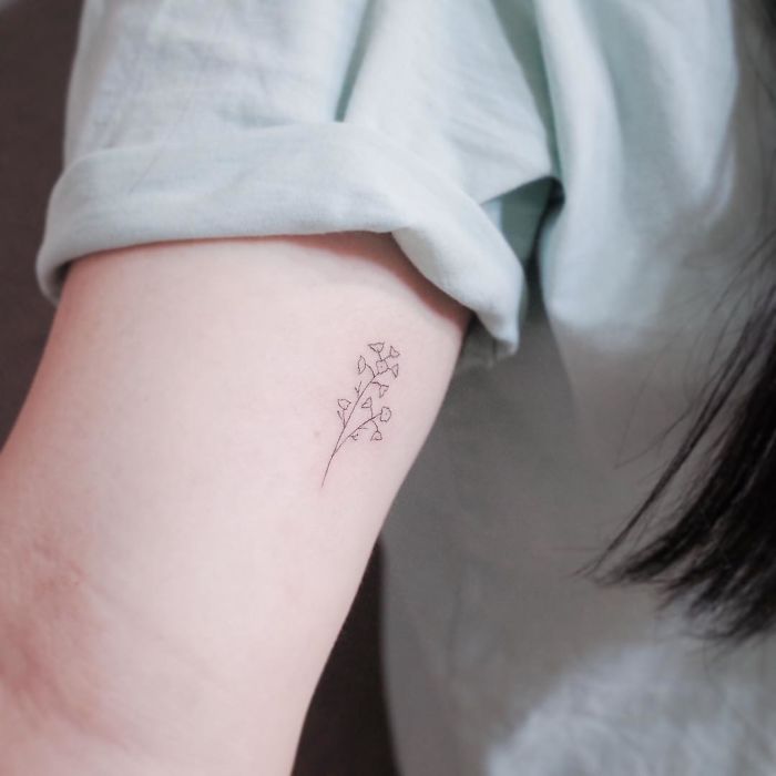 Minimalist tattoo of a delicate flower on an arm, showcasing tiny discreet design.