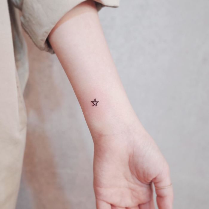 Minimalist tiny star tattoo on a wrist, showcasing discreet design for tattoo enthusiasts.