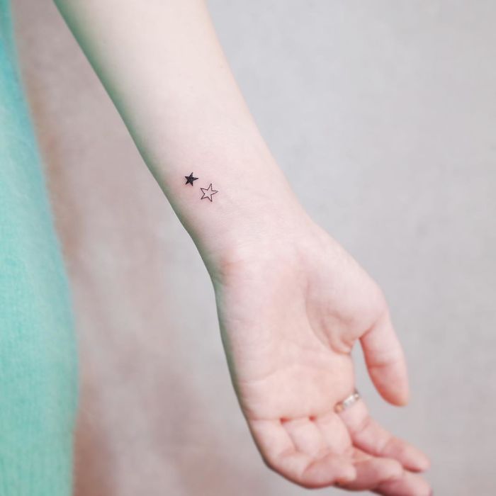 Minimalism tattoo of two tiny stars on a wrist, showing discreet and elegant design.