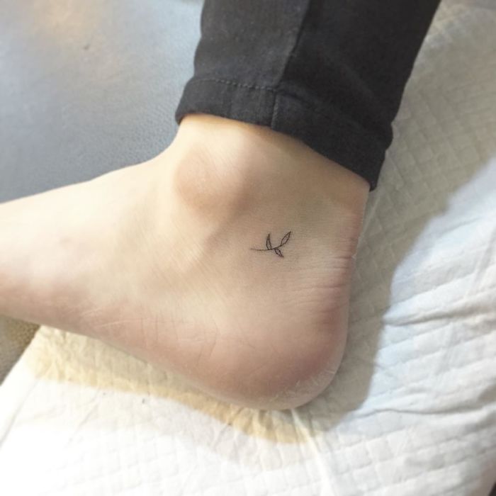 Minimalist tiny tattoo of a leaf on an ankle.