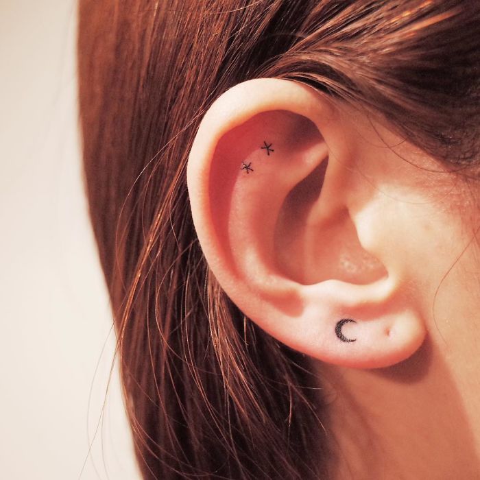 Minimalist tiny discreet ear tattoos with stars and a crescent moon.