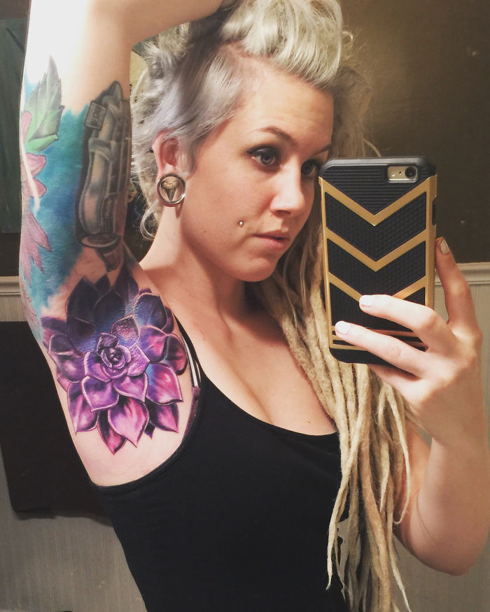 Woman taking a selfie showing off a colorful succulent tattoo on her arm.