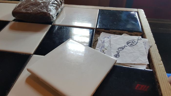 Table At Local Bar Has A Tile That Lifts Up To Reveal A Stash Of Hidden Notes