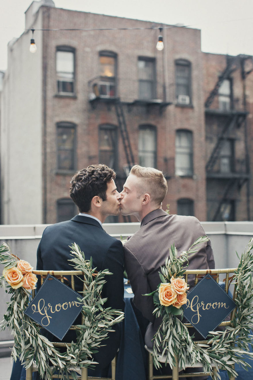 Two men kissing on a buildings roof 