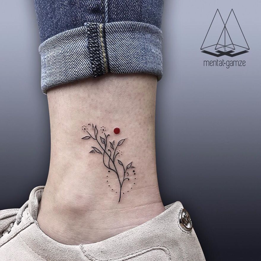 Minimalist tattoo with a red dot and floral design on an ankle, showcasing a tattoo artist's unique creation.