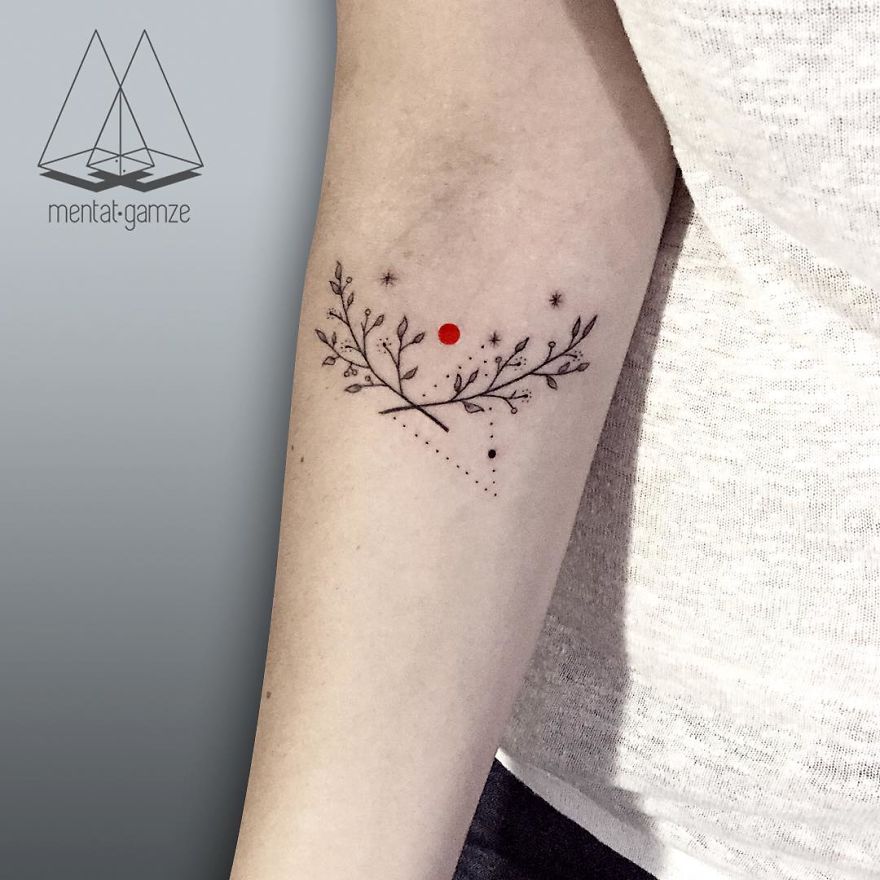 Elegant tattoo design featuring delicate branches and a prominent red dot.