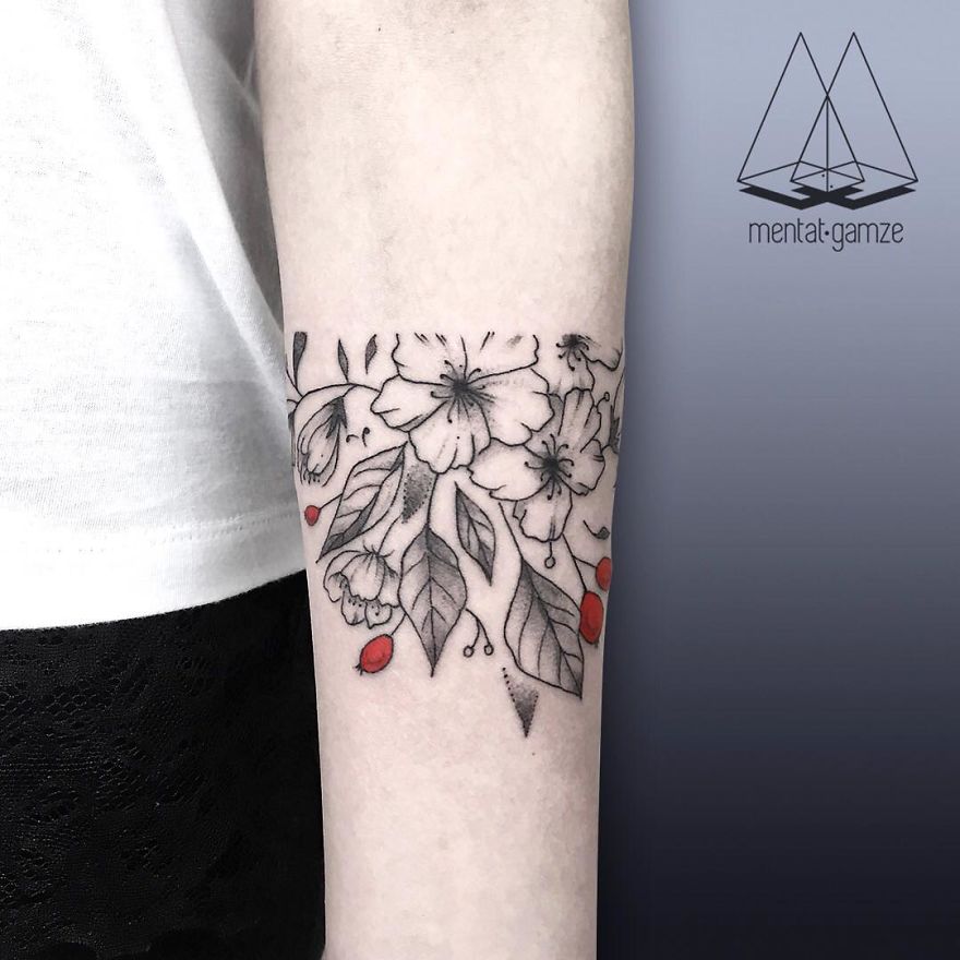 Floral tattoo with red dots on forearm, showcasing creative tattoo artist's work from a new career path.
