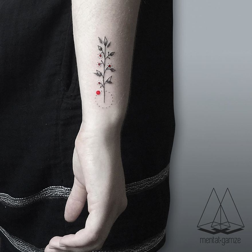 A tattoo of a delicate plant with red dots on a person's forearm, showcasing tattoo artistry skills.