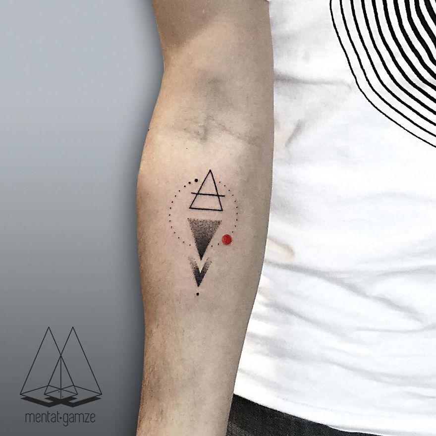 Geometric tattoo with a red dot on a person's forearm, showcasing a unique design.