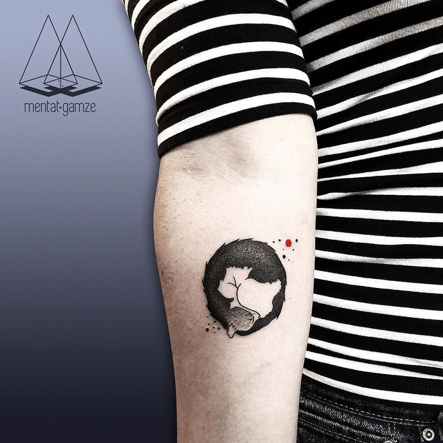 Arm tattoo featuring a cat within a black circle and red dot, created by a former job quitter turned tattoo artist.