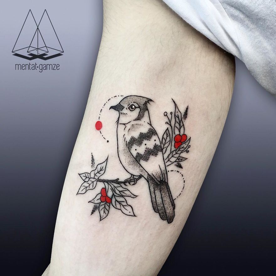 Tattoo art featuring a bird and red dot on a person's arm, showcasing a creative design by a tattoo artist.