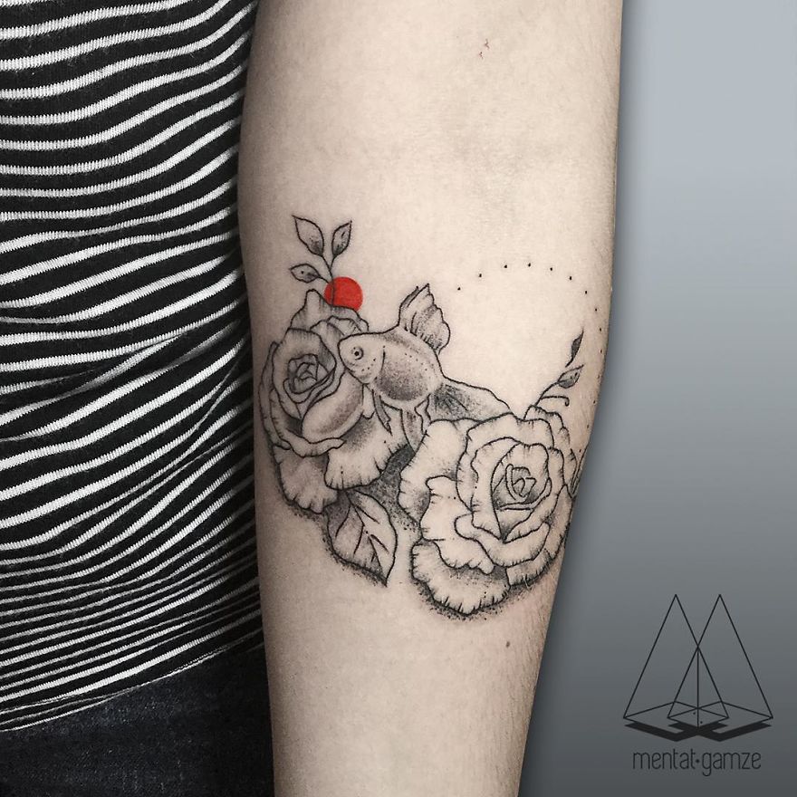 Tattoo of roses and a fish with a red dot on an arm, created by a former boring job worker turned tattoo artist.