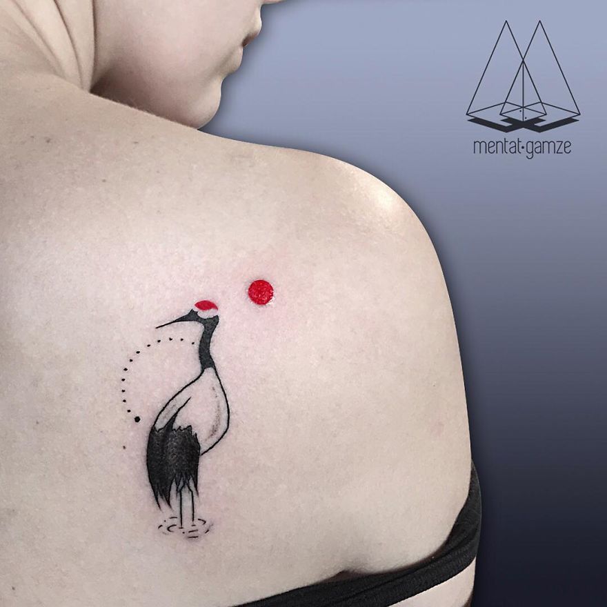 Tattoo of a crane with a red dot on a person's shoulder, showcasing artistic work of a tattoo artist.