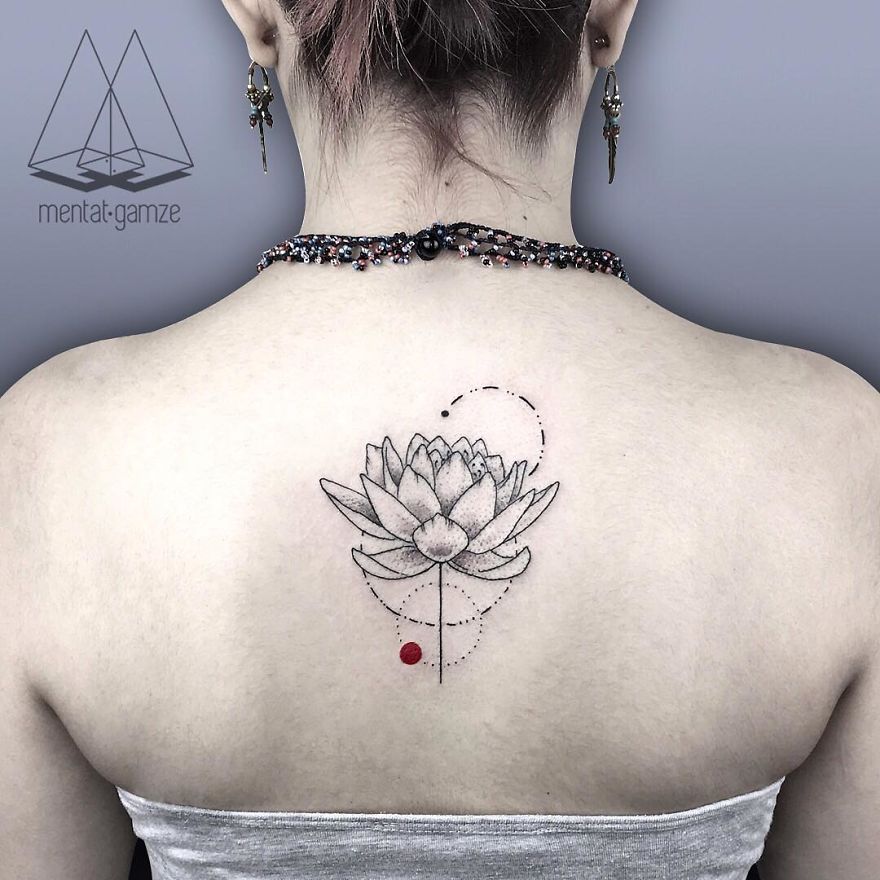 Lotus tattoo with a red dot on a woman's upper back, symbolizing creative transition to a tattoo artist career.