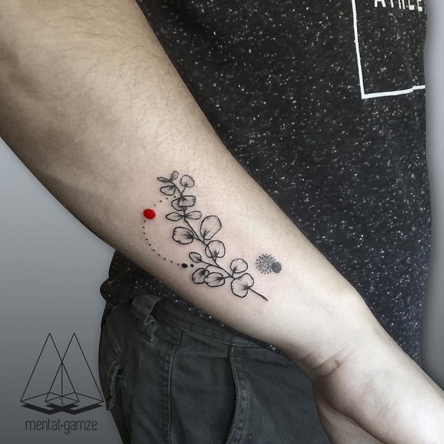 Tattoo with a red dot and abstract leaf design on an arm, showcasing creative tattoo artistry.