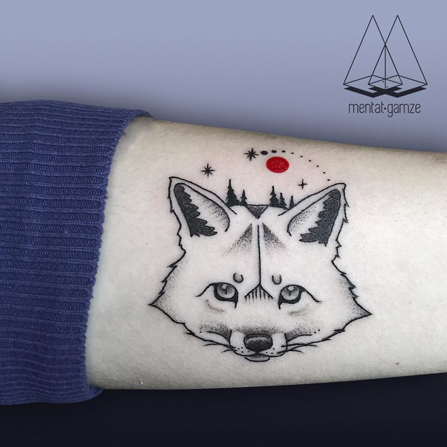 Wolf tattoo with red dot and stars on arm, showcasing unique tattoo art style.