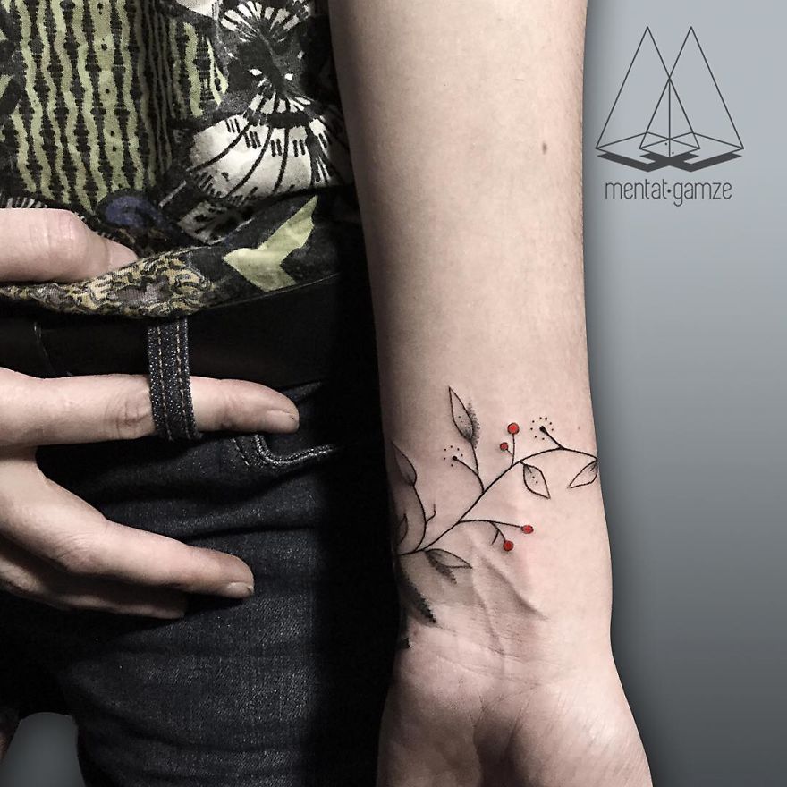 Tattoo artist's floral design with red dots on a forearm, showcasing creative tattoo art.