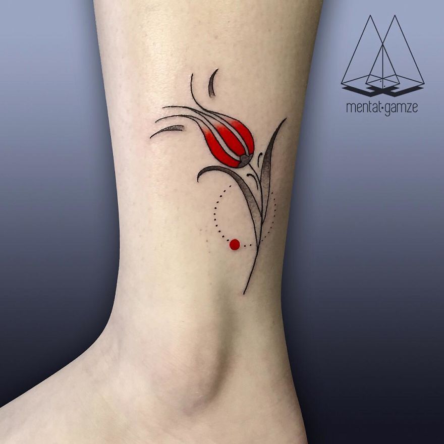 Minimalist tattoo featuring a red dot and floral design on an ankle.
