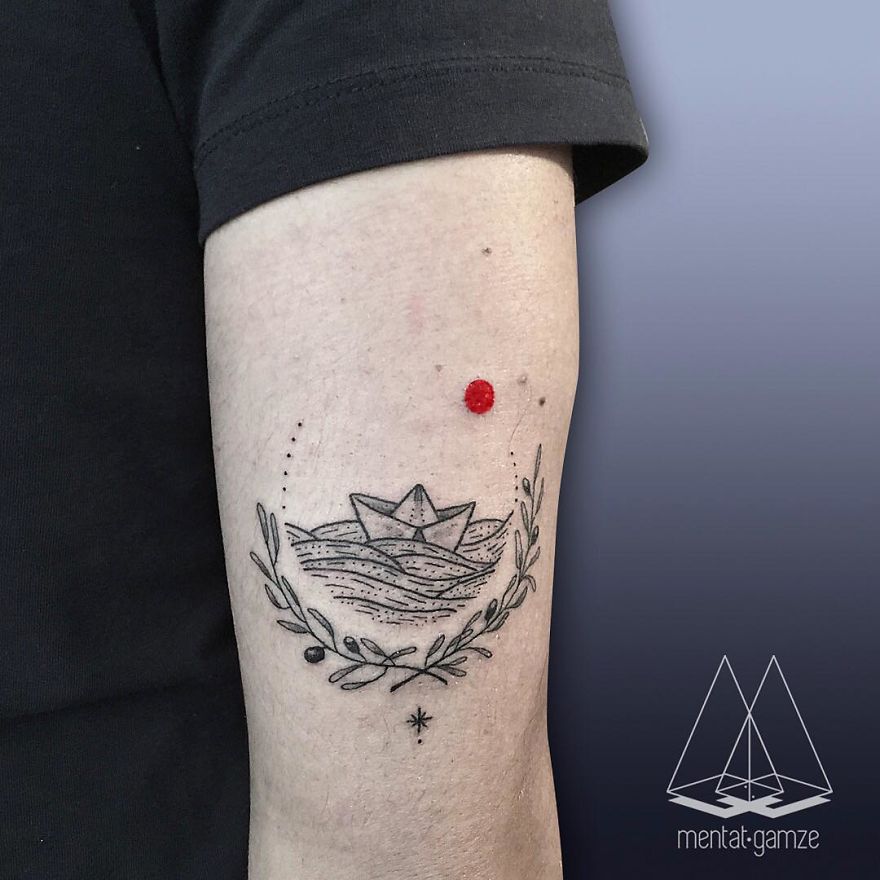 Tattoo of a paper boat with a red dot on arm, showcasing a tattoo artist's creative design.