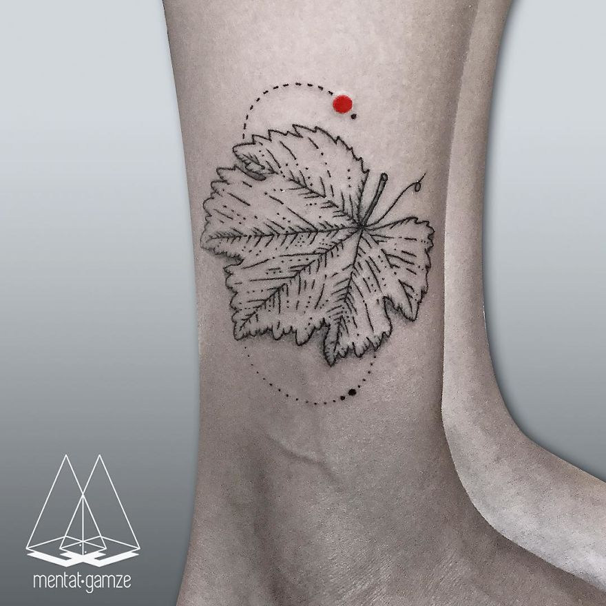 Tattoo of a leaf with a red dot on skin, showcasing unique artistry and style.
