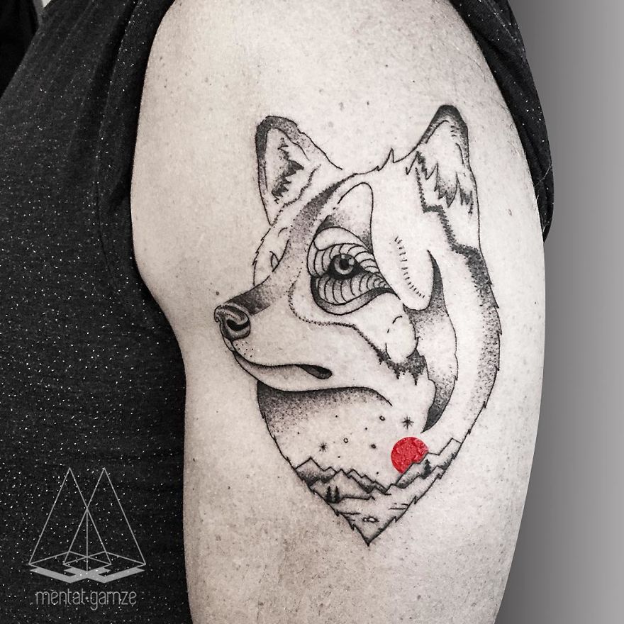 Wolf tattoo design with a red dot, featuring geometric elements on an upper arm.