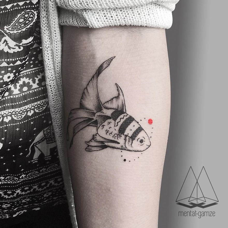Tattoo artist's fish design with a red dot on forearm, showcasing intricate line work and artistry.