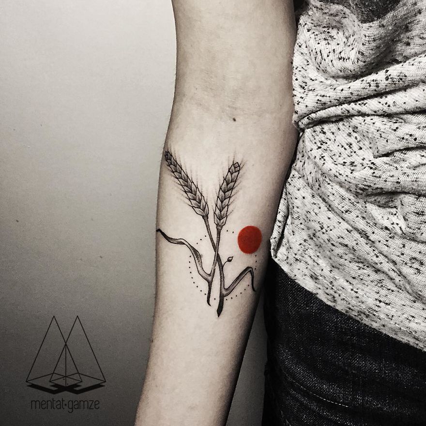 Tattoo artist's design featuring wheat stems with a vibrant red dot on an arm.