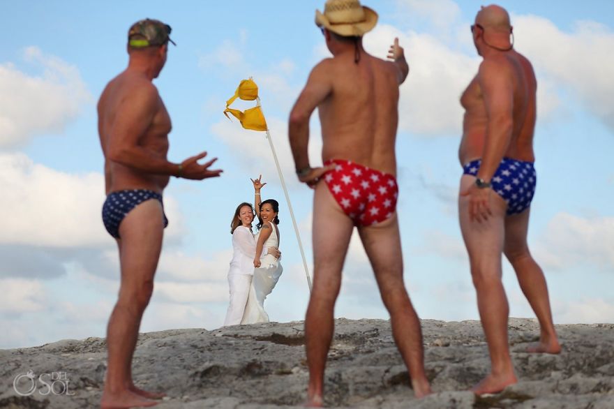 Three men in underwear looking at two happy woman hugging 