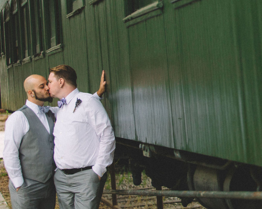Two men kissing near a train 