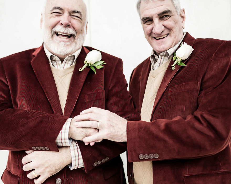 Two old man in red suits laughing 