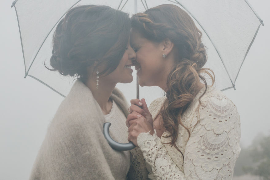 Two woman kissing and holding an umbrella 