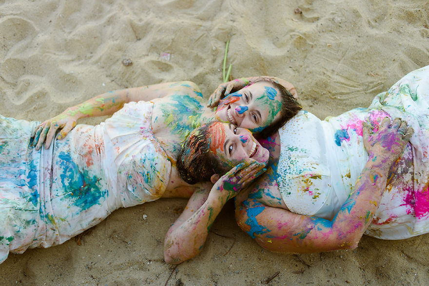 Two woman covered in paint laying in the beach 