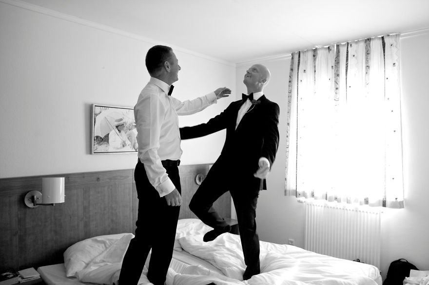 Two men standing on bed 