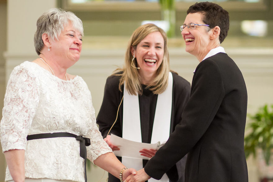 Two happy woman standing near a pastor 