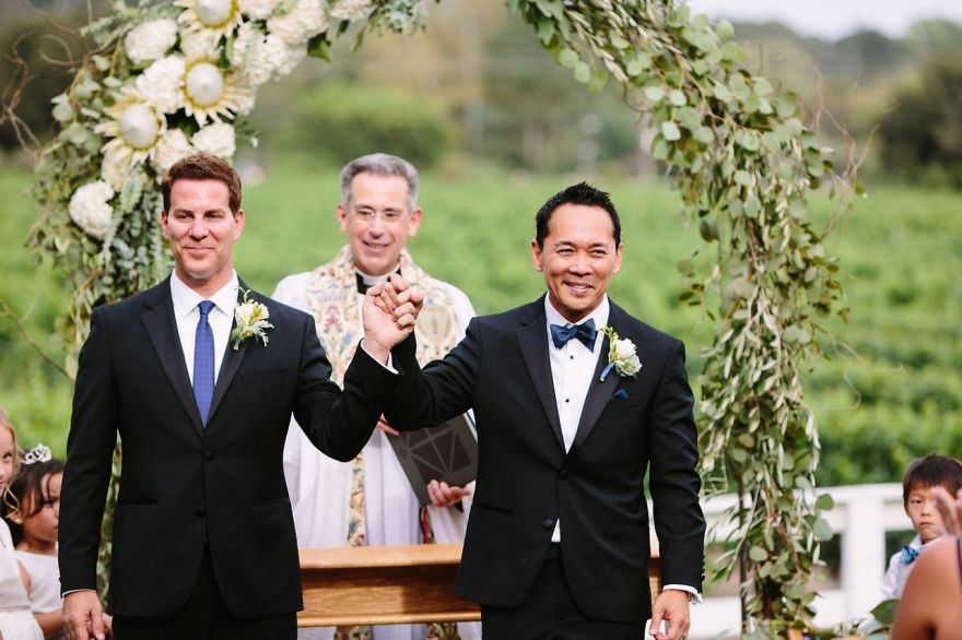 Two men holding hands near an altar 