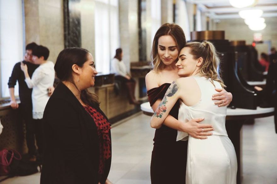 Two happy women hugging near a pastor 